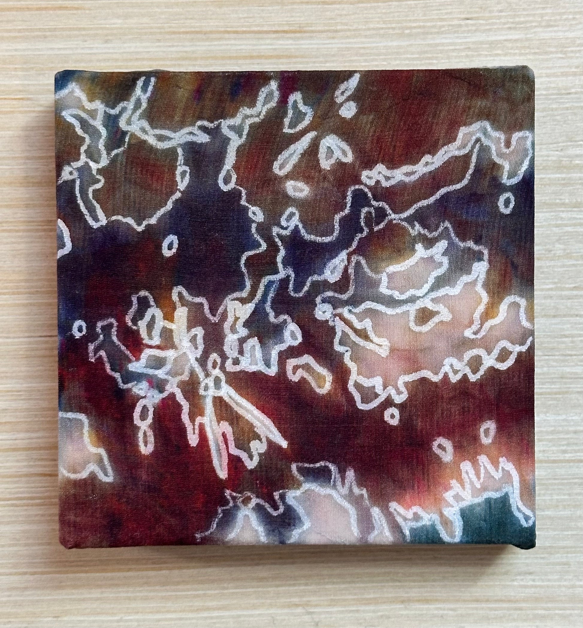 Square painting with abstract design on a wooden surface