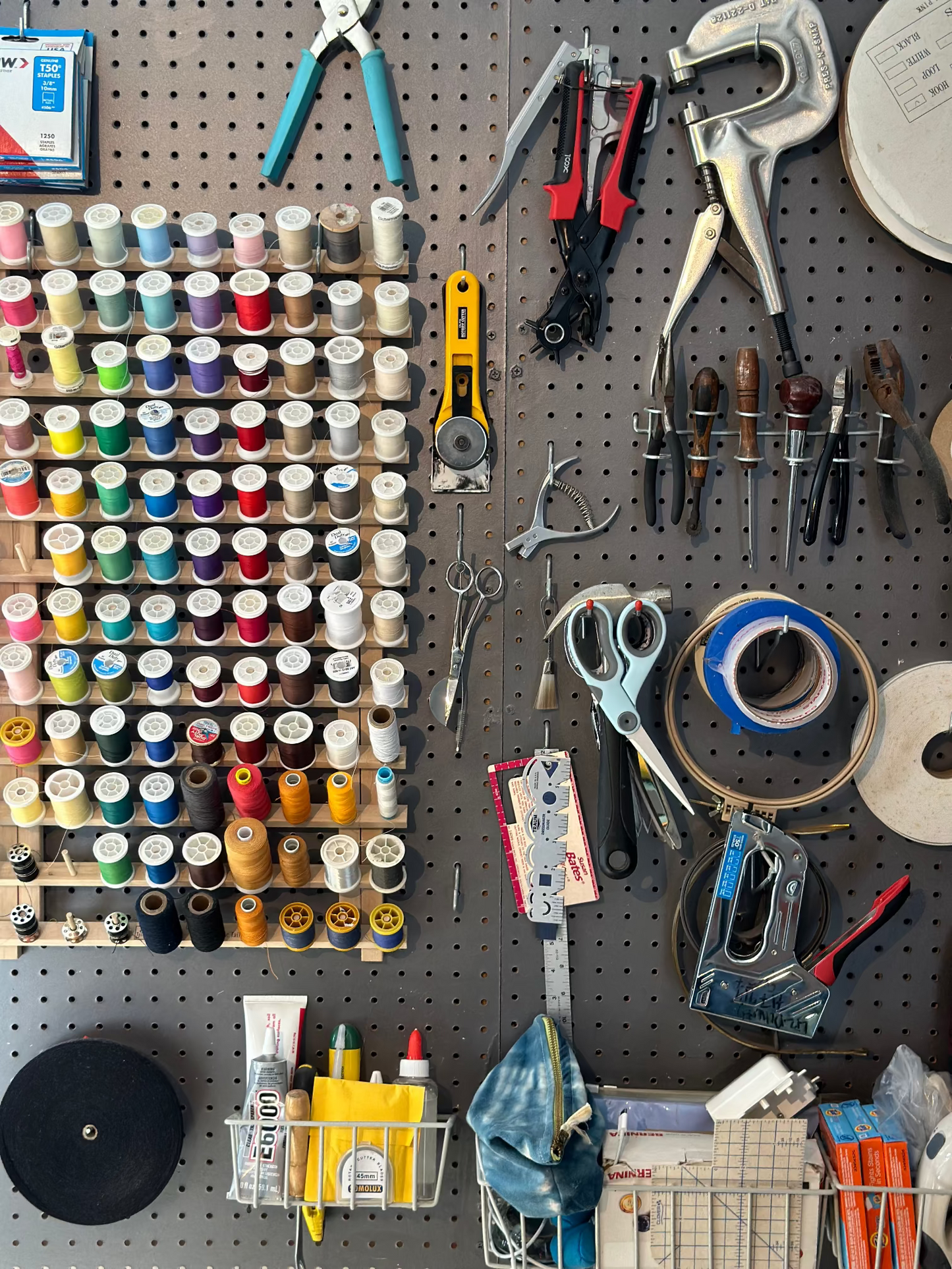  pegboard with various tools and supplies including spools of thread and pliers