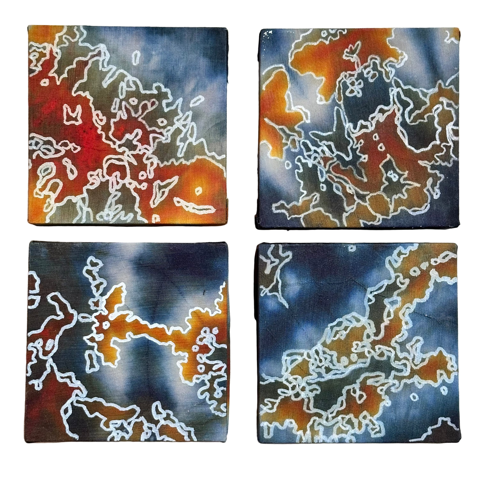 Four square silk paintings with white abstract design on a wooden surface